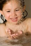 Image of my daughter amused with the water droplets falling from the shower while she was enjoying her bath.