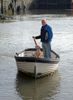 After spending a morning getting his fishing boat ready for the next trip this fisherman and his dog rowed across the harbour on the way home.